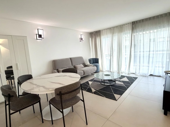 Salon lumineux d'un appartement de 3 pièces à Cannes, avec un canapé, une table et des grandes fenêtres.
