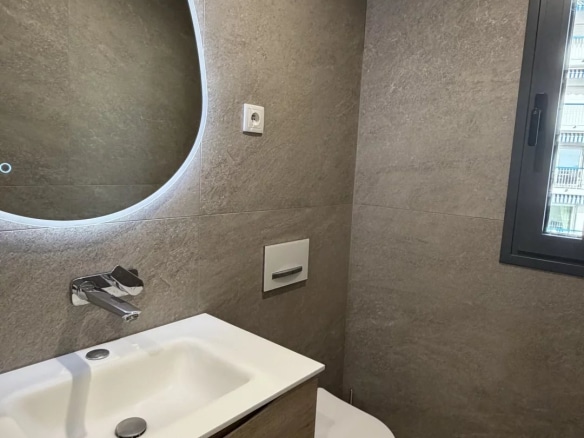 Salle de bain moderne avec lavabo et toilettes, murs en carrelage gris
