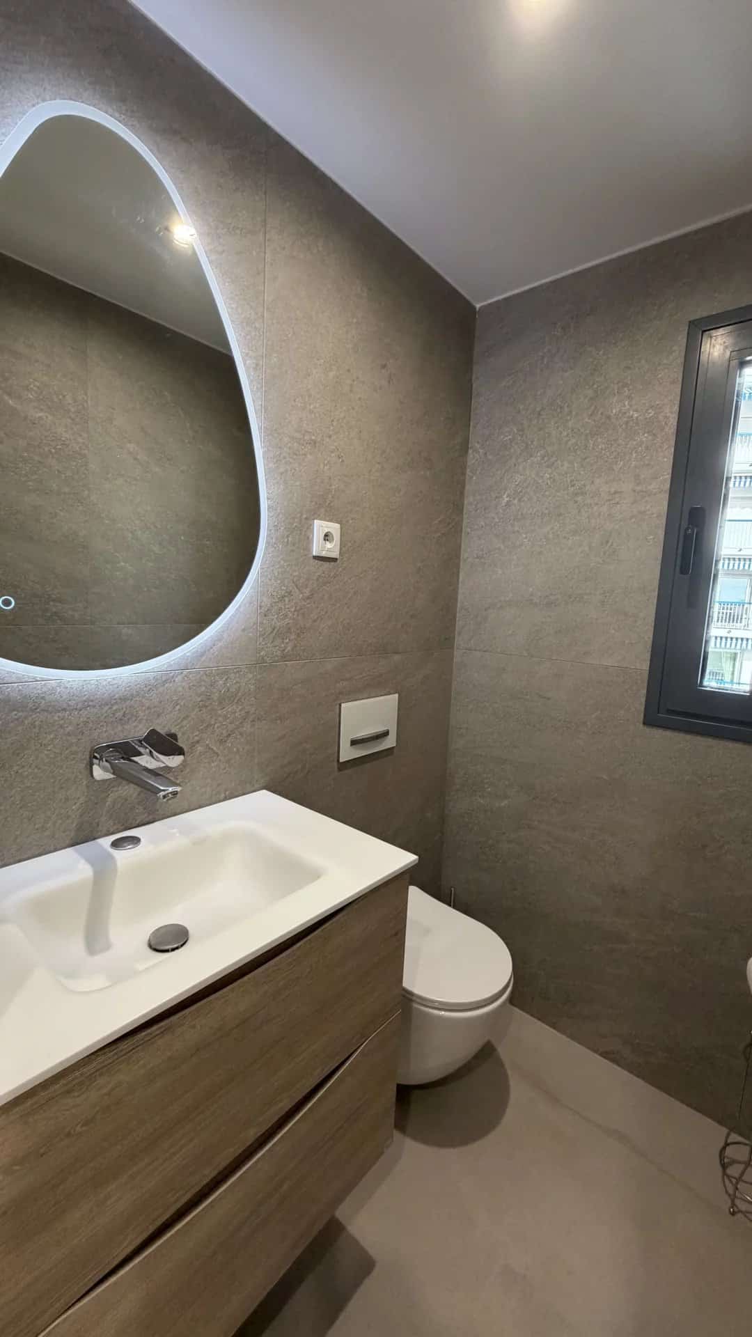 Salle de bain moderne avec lavabo et toilettes, murs en carrelage gris