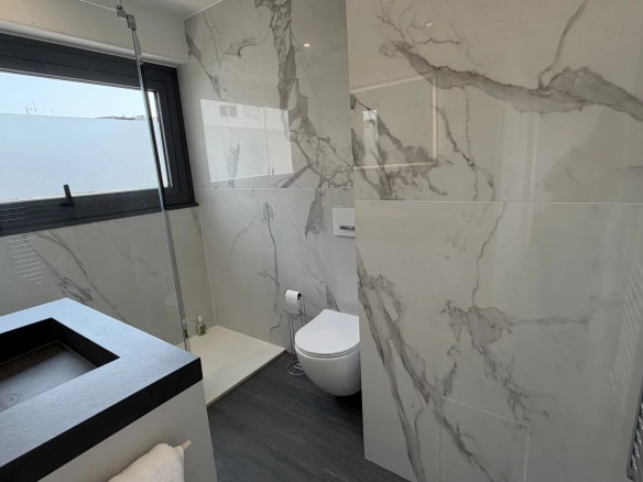 Modern bathroom with marble tiles and walk-in shower.