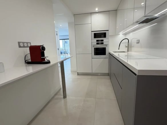 Modern and bright kitchen in an apartment in Cannes, with integrated appliances and quartz worktop.