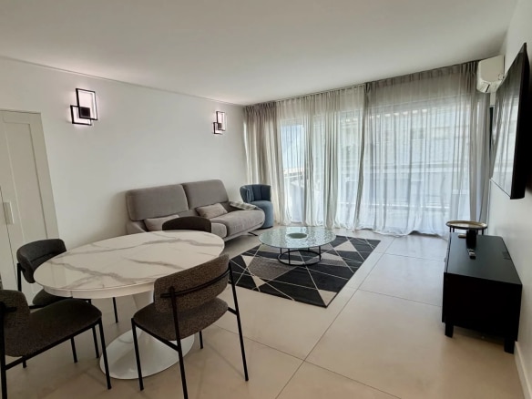 Interior of a bright apartment in Cannes, with living room, dining table and terrace.