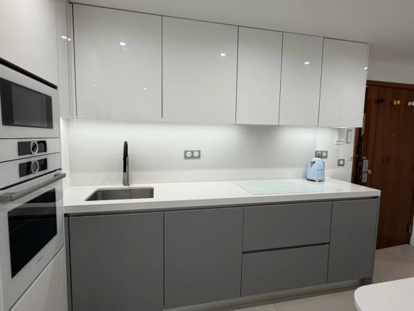 Modern and bright kitchen with grey and white furniture, integrated sink and appliances.