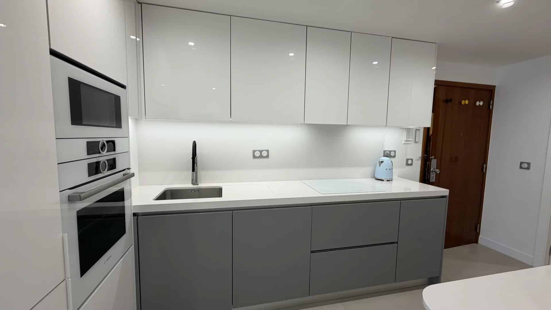 Modern cuisine in Palm Beach Modern and bright kitchen with grey and white furniture, integrated sink and appliances.