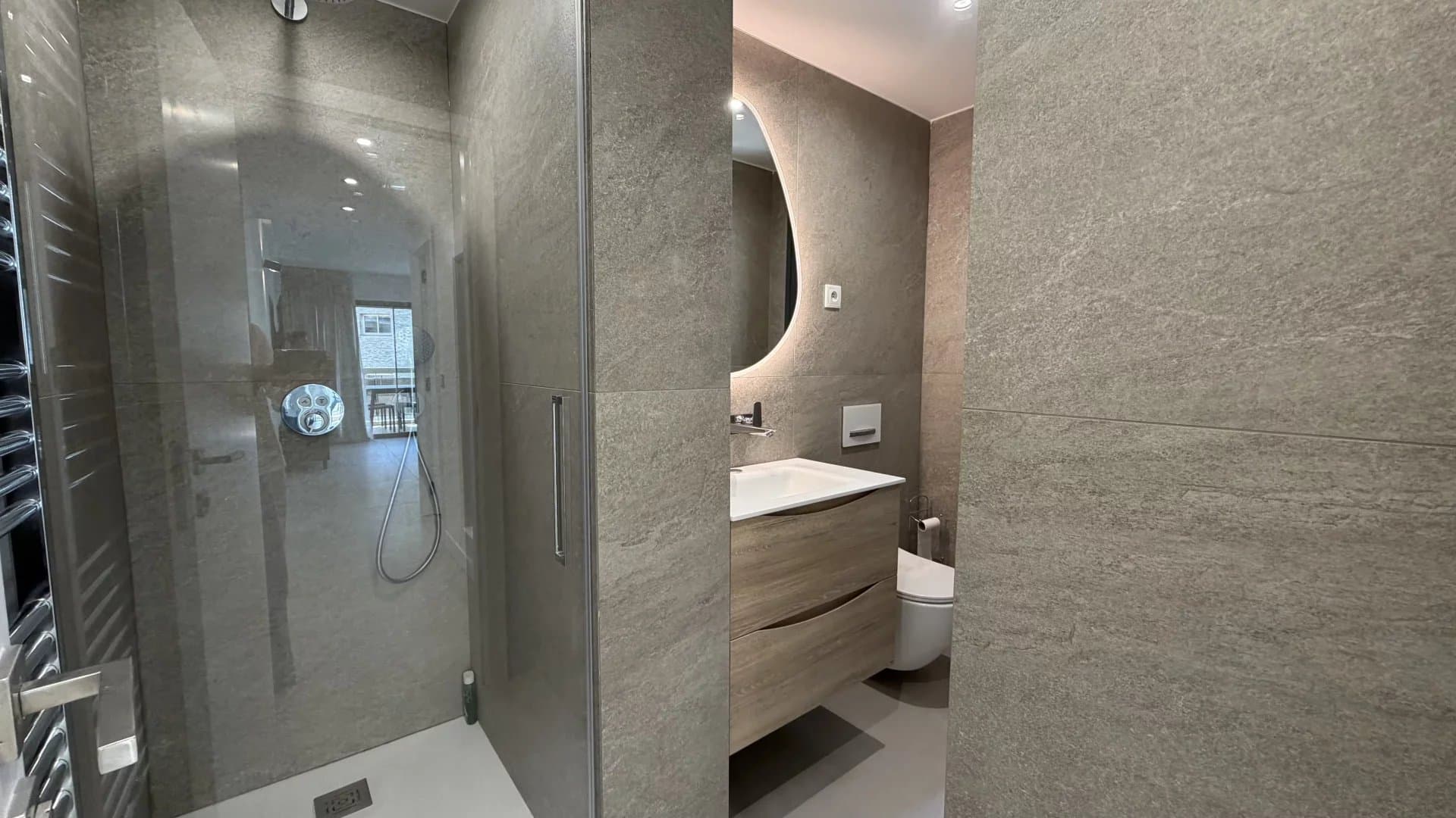 Bathroom of the apartment in Palm Beach Modern bathroom with walk-in shower and wooden vanity unit.