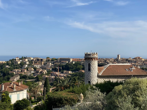 Panoramic view of Vence with the sea in the distance and historic buildings.