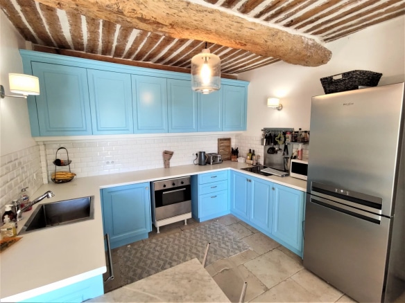 Cuisine moderne avec meubles bleus et éléments en bois, rénovée dans une maison ancienne à Mougins.