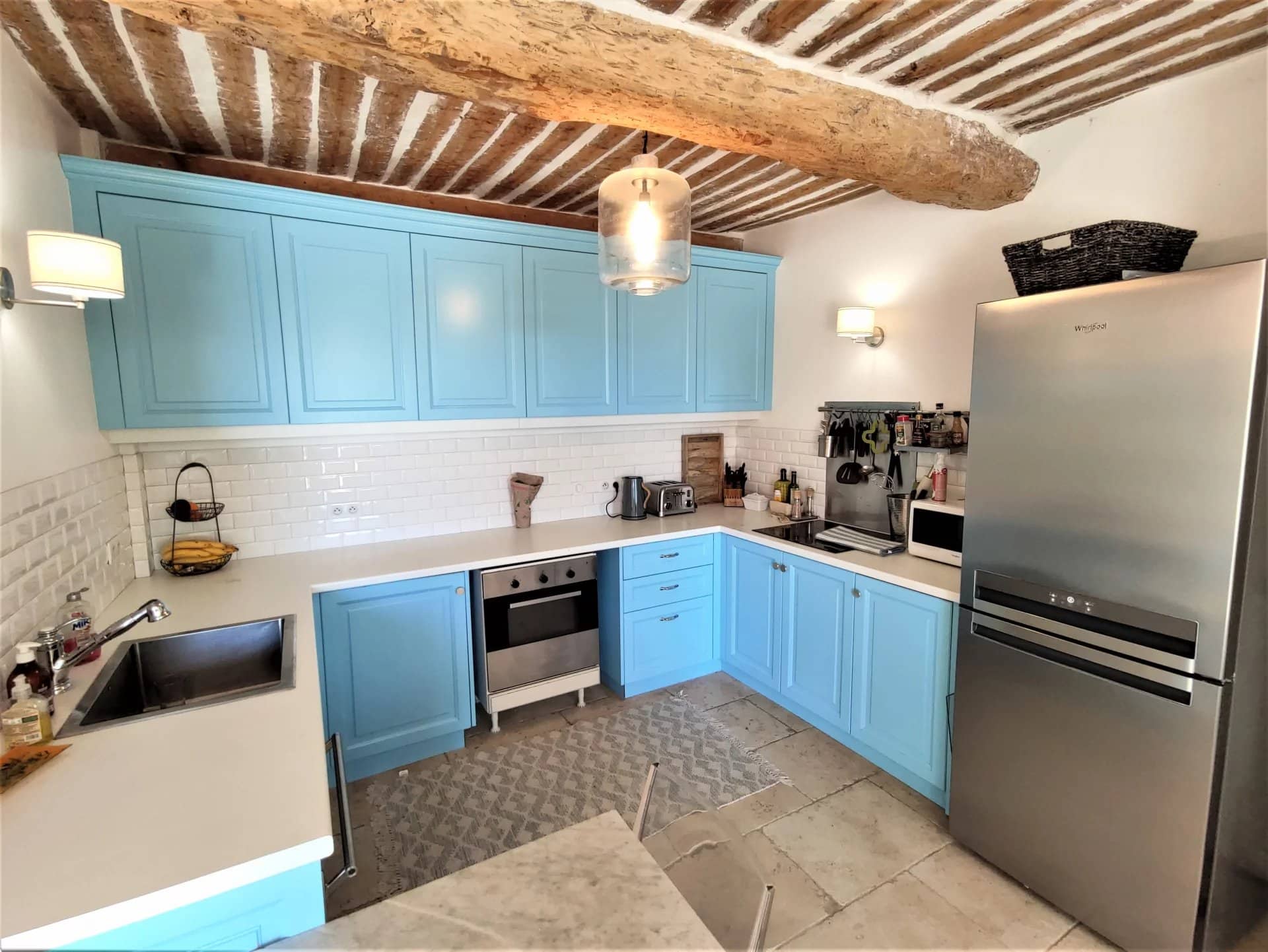 Cuisine moderne avec meubles bleus et éléments en bois, rénovée dans une maison ancienne à Mougins.