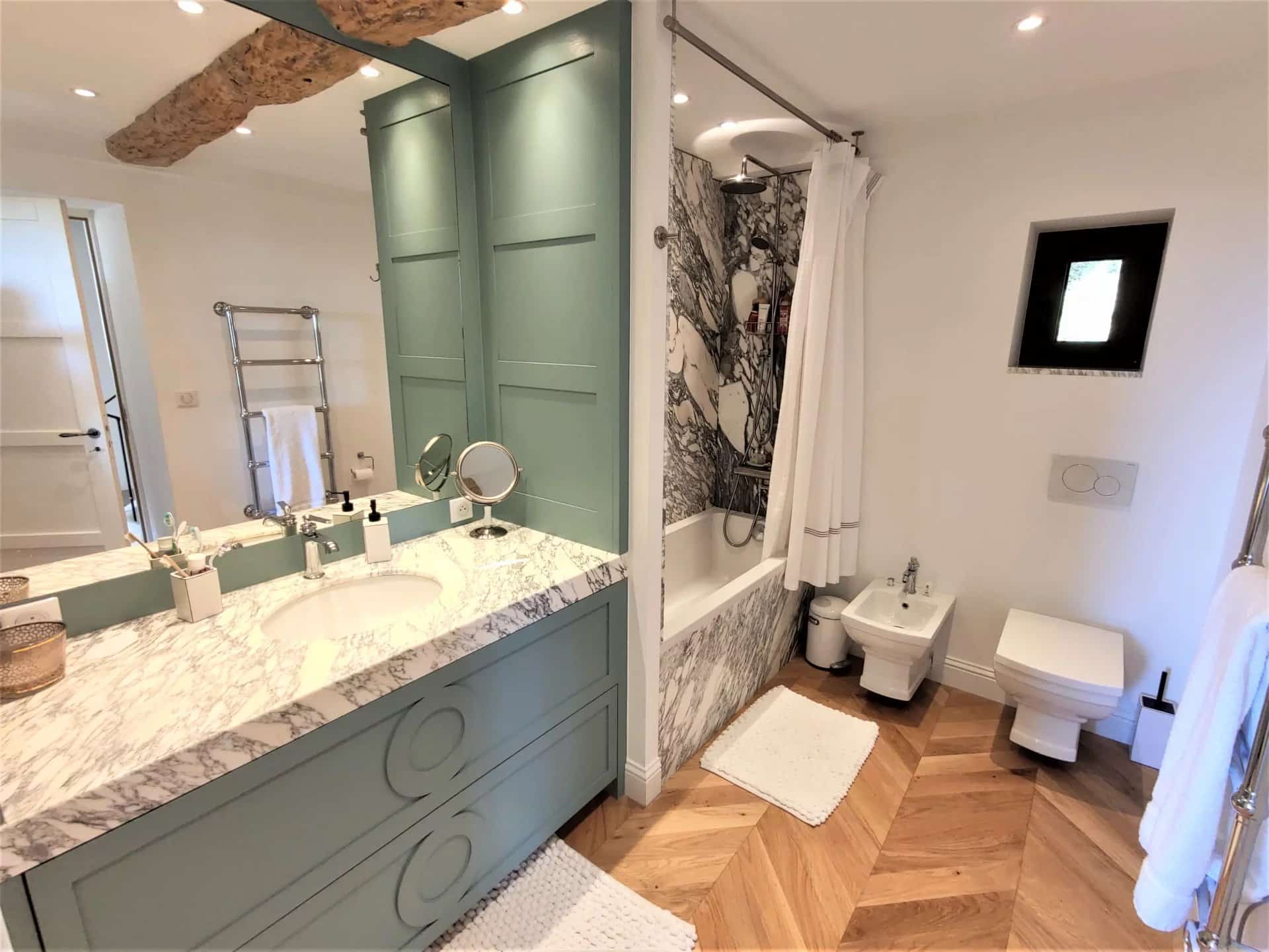 Salle de bain moderne avec double vasque et baignoire, décorée de marbre et de bois.