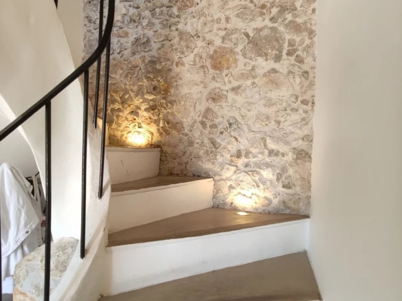 Escalier en colimaçon avec murs en pierre et éclairage doux.
