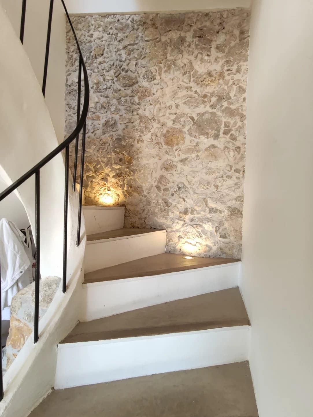 Escalier en colimaçon avec murs en pierre et éclairage doux.