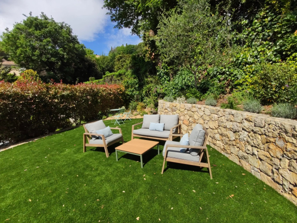 Espace extérieur d'une villa à Mougins avec mobilier de jardin sur une pelouse verte.