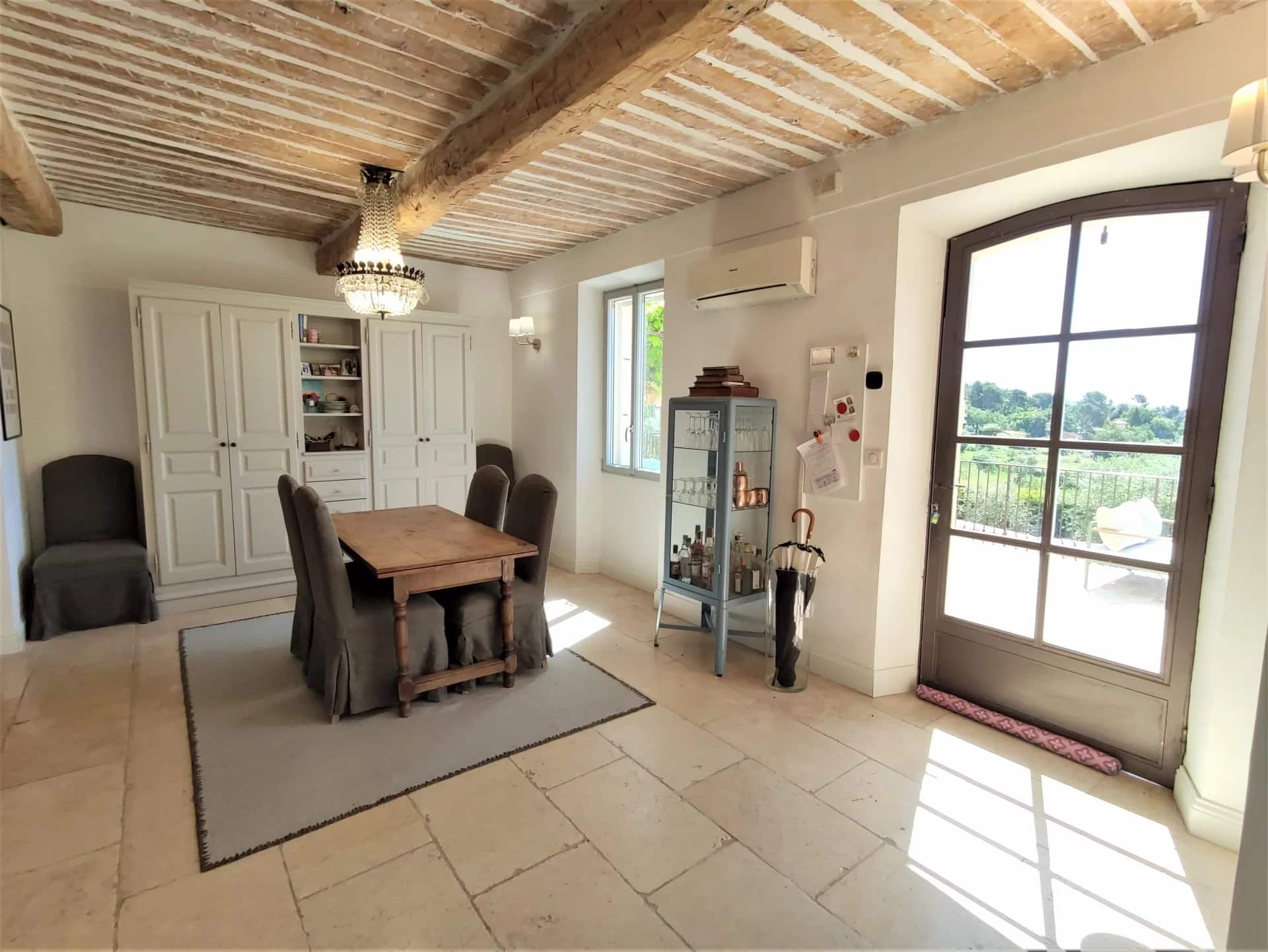 Intérieur d'une maison rénovée avec un salon lumineux et une table à manger en bois.