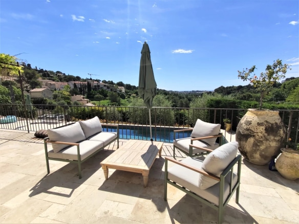 Terrasse avec fauteuils et table, vue sur piscine et paysage à Mougins.