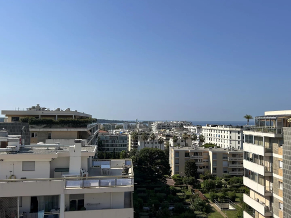 Panoramic view of Cannes from a terrace, with the sea in the distance and residential buildings in the foreground.