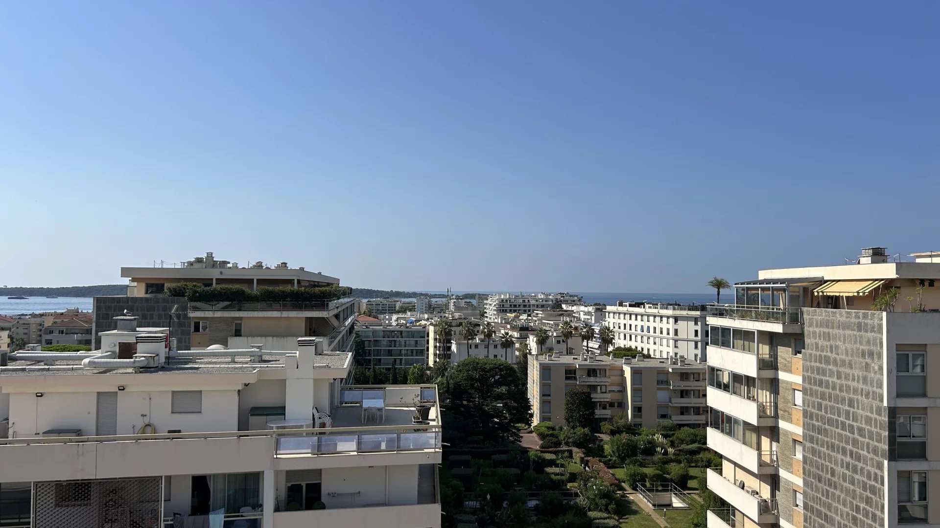 View of Cannes from the terrace Panoramic view of Cannes from a terrace, with the sea in the distance and residential buildings in the foreground.