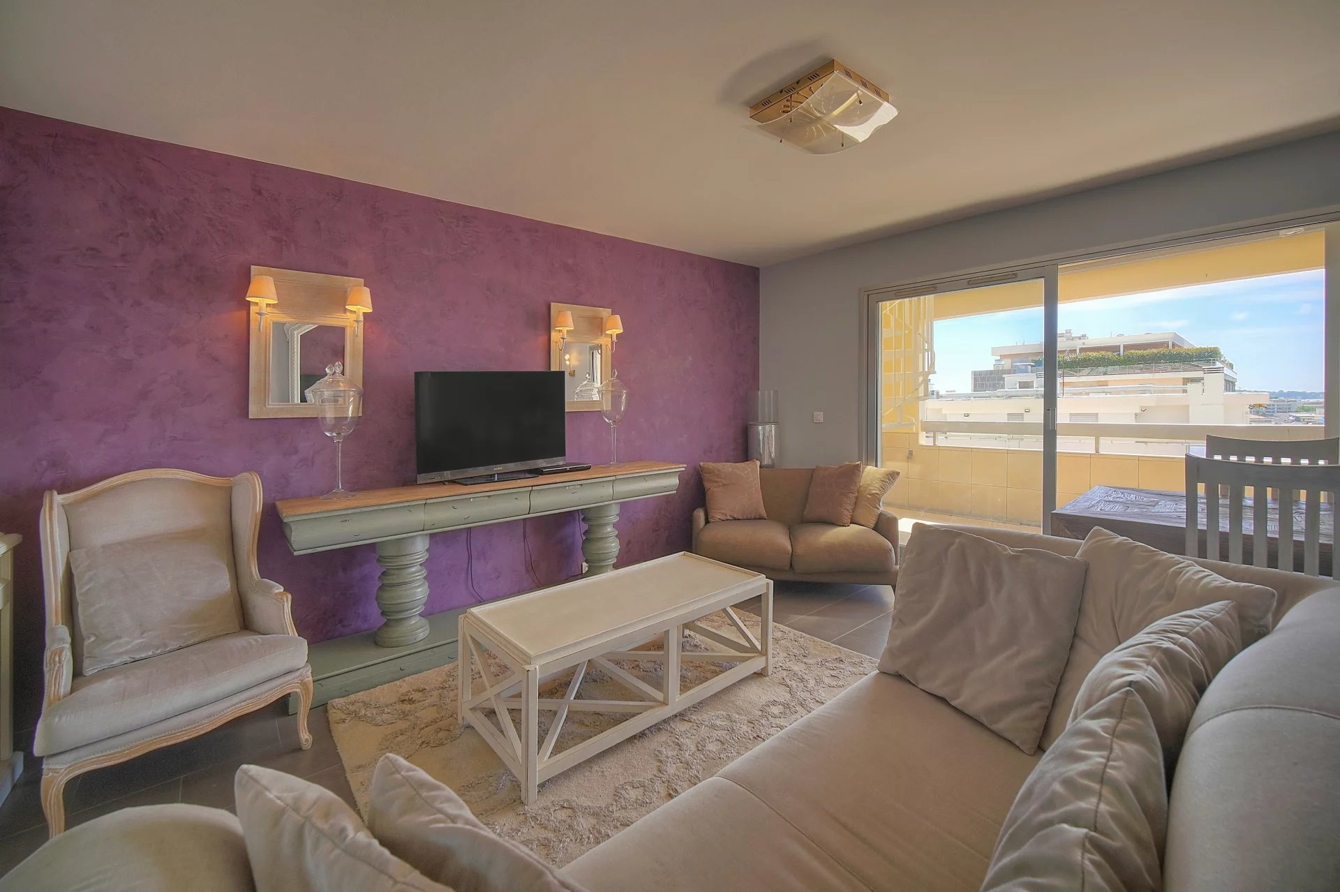 Intérieur d'un appartement à Cannes avec un salon lumineux et un accès à une terrasse.