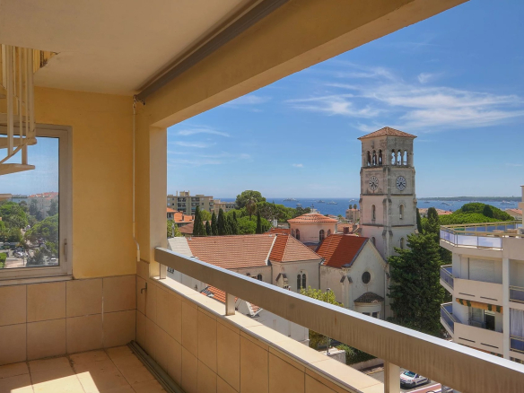 Vue depuis une terrasse d'appartement à Cannes, avec mer et bâtiments environnants.