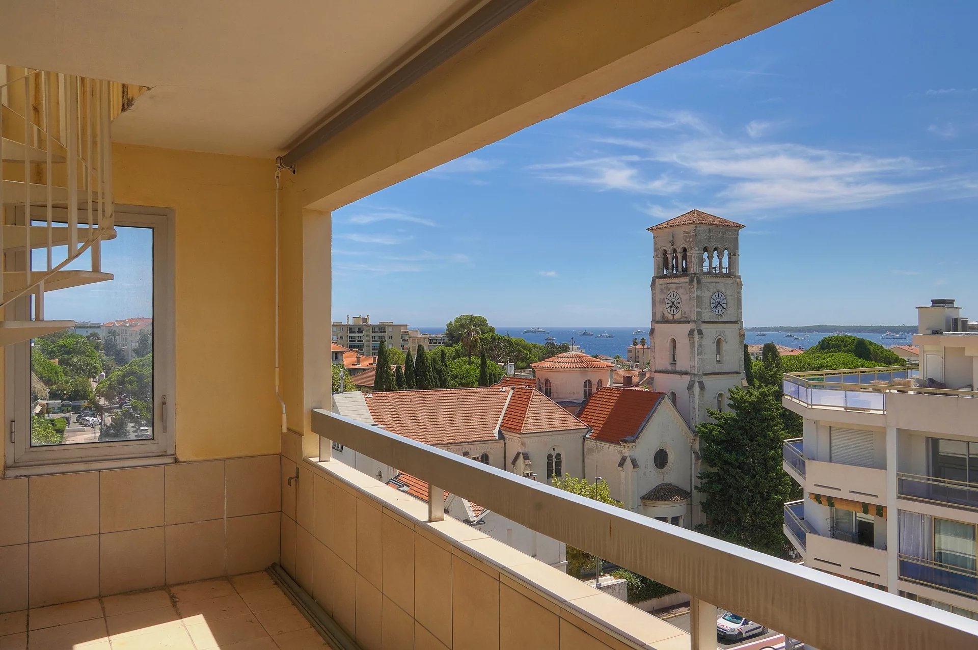 Vue depuis une terrasse d'appartement à Cannes, avec mer et bâtiments environnants.
