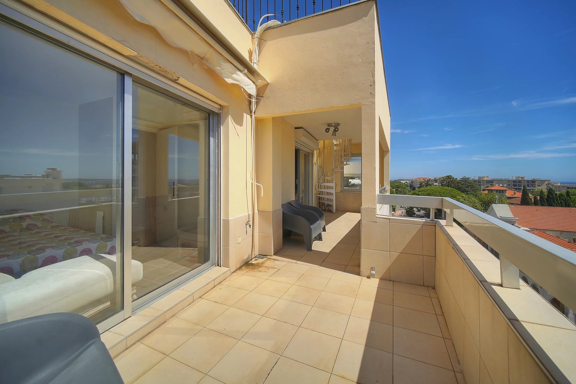 Terrasse d'un appartement à Cannes avec vue sur la mer, mobilier extérieur visible.