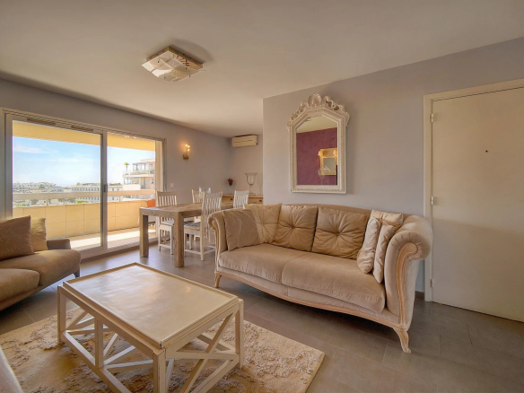 Intérieur d'un appartement à Cannes avec vue sur la mer, salon et salle à manger lumineux.
