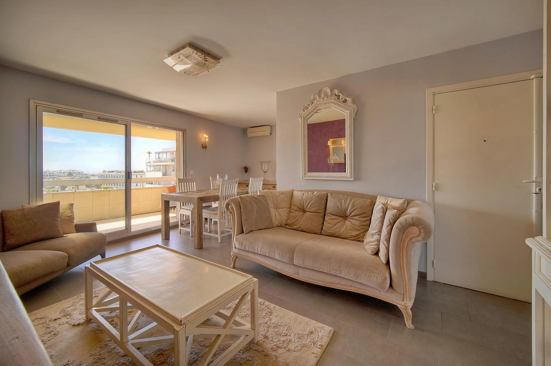 Intérieur d'un appartement à Cannes avec vue sur la mer, salon et salle à manger lumineux.