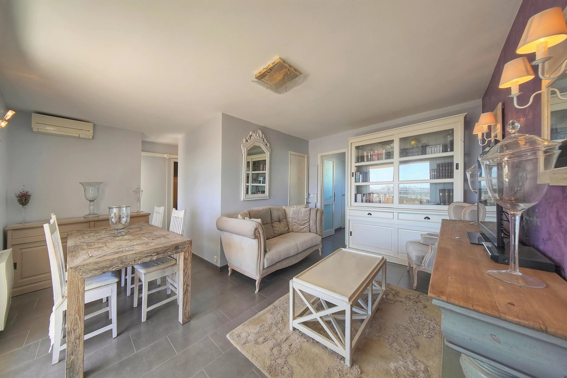 Intérieur d'un appartement à Cannes avec salon, salle à manger et vue sur la mer.
