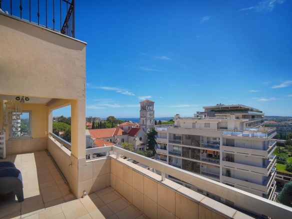 Vue depuis une terrasse d'appartement à Cannes, avec mer en arrière-plan et bâtiments environnants.