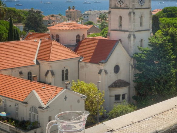 Vue depuis une terrasse avec un pichet et des verres, surplombant des maisons et la mer à Cannes.