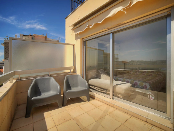 Terrasse d'un appartement à Cannes avec vue sur la mer, deux chaises en plastique sur le balcon.