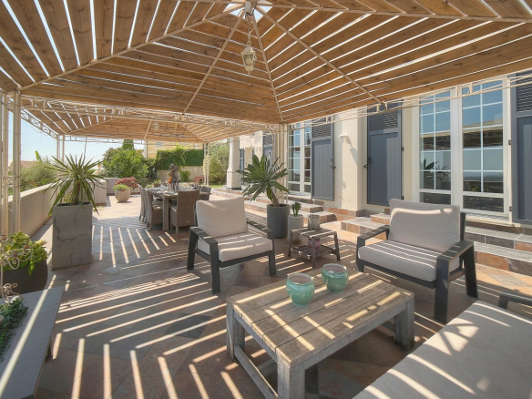 Terrasse ensoleillée avec mobilier de jardin et vue dégagée sur la mer.