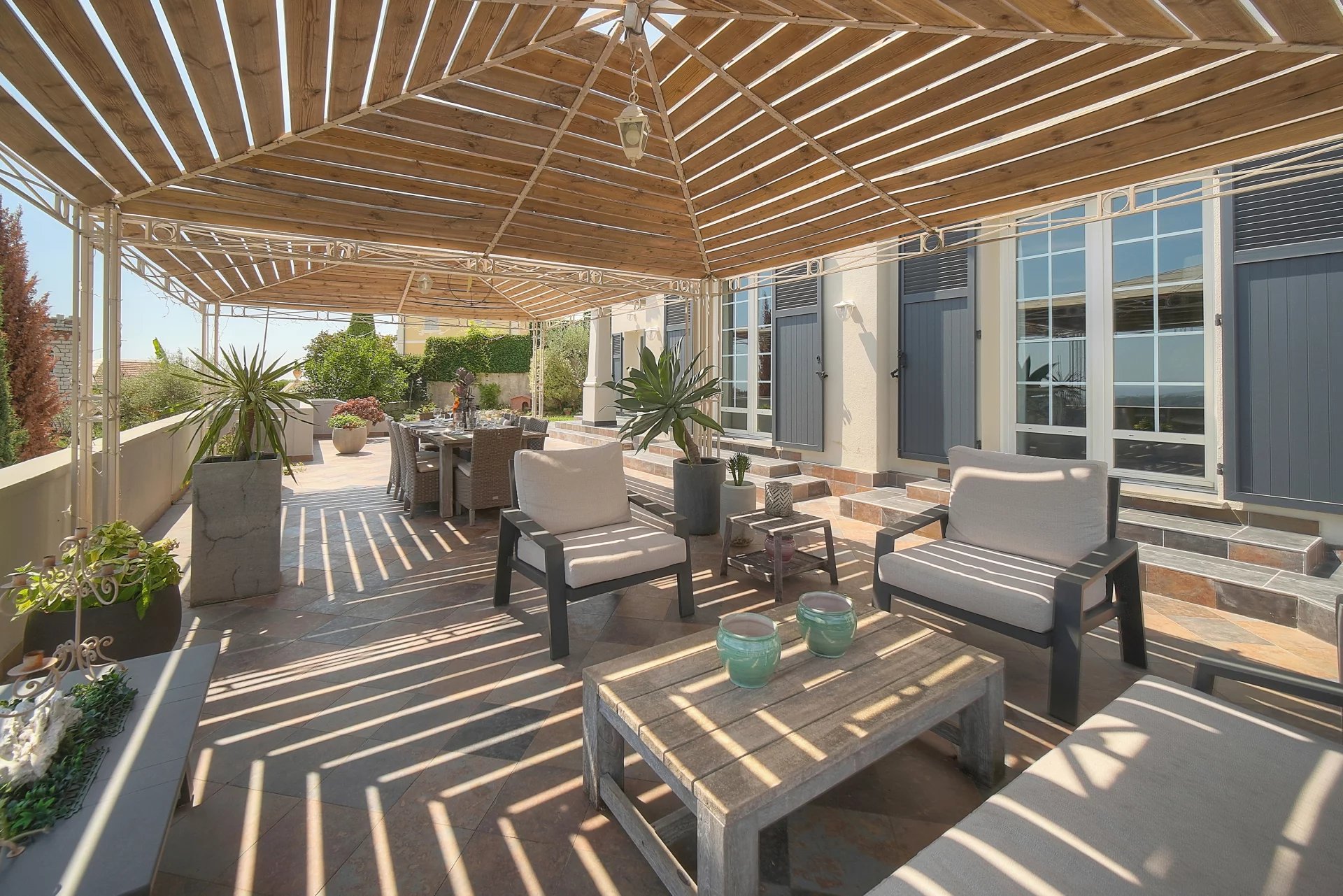 Terrasse de villa à Vence Terrasse ensoleillée avec mobilier de jardin et vue dégagée sur la mer.