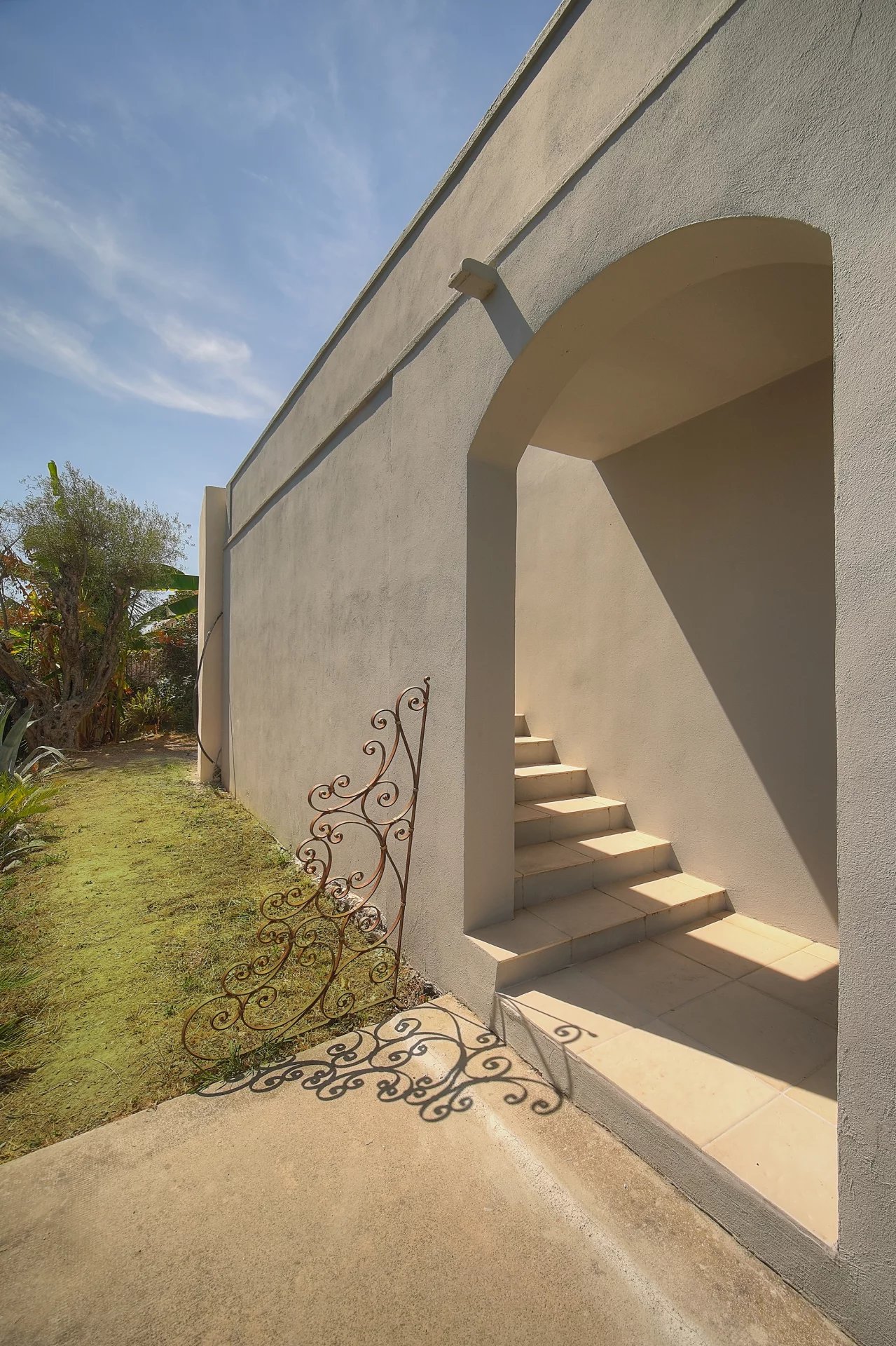 Escalier d’entrée d’une villa à Vence Escalier menant à l'entrée d'une villa à Vence, avec un mur gris et un jardin à côté.