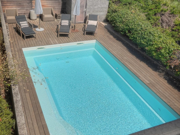Vue de la piscine et du jardin d'une villa à Vence, avec des chaises longues et des parasols.
