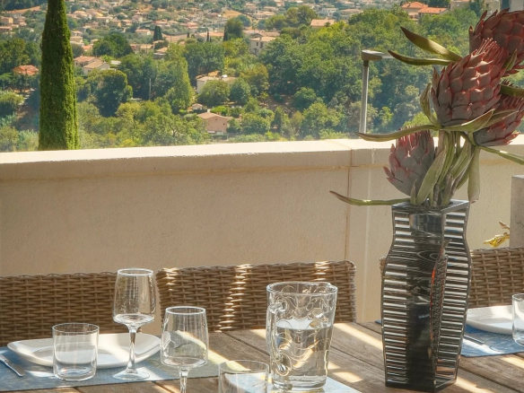 Terrasse d'une villa à Vence avec vue sur la mer et la ville, table dressée pour le repas.