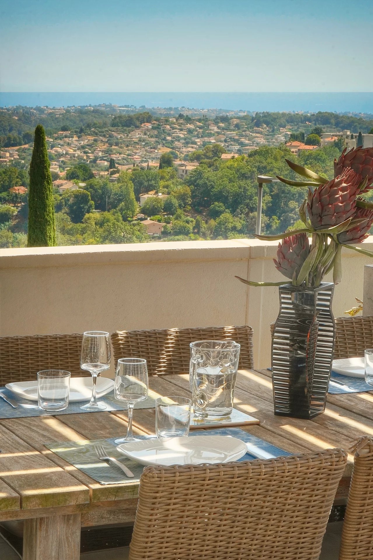 Terrasse avec vue mer à Vence Terrasse d'une villa à Vence avec vue sur la mer et la ville, table dressée pour le repas.
