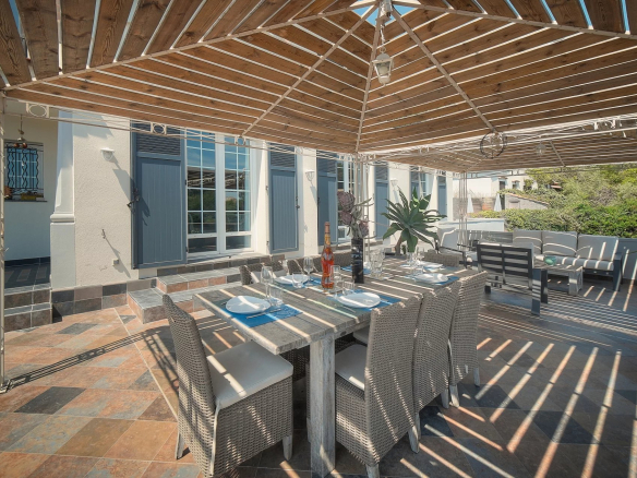 Terrasse d'une villa à Vence avec table à manger et chaises, ombragée par un auvent en bois.