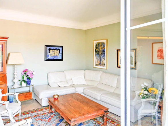 Salon lumineux d'un appartement bourgeois à Cannes, avec canapé blanc et table basse en bois.