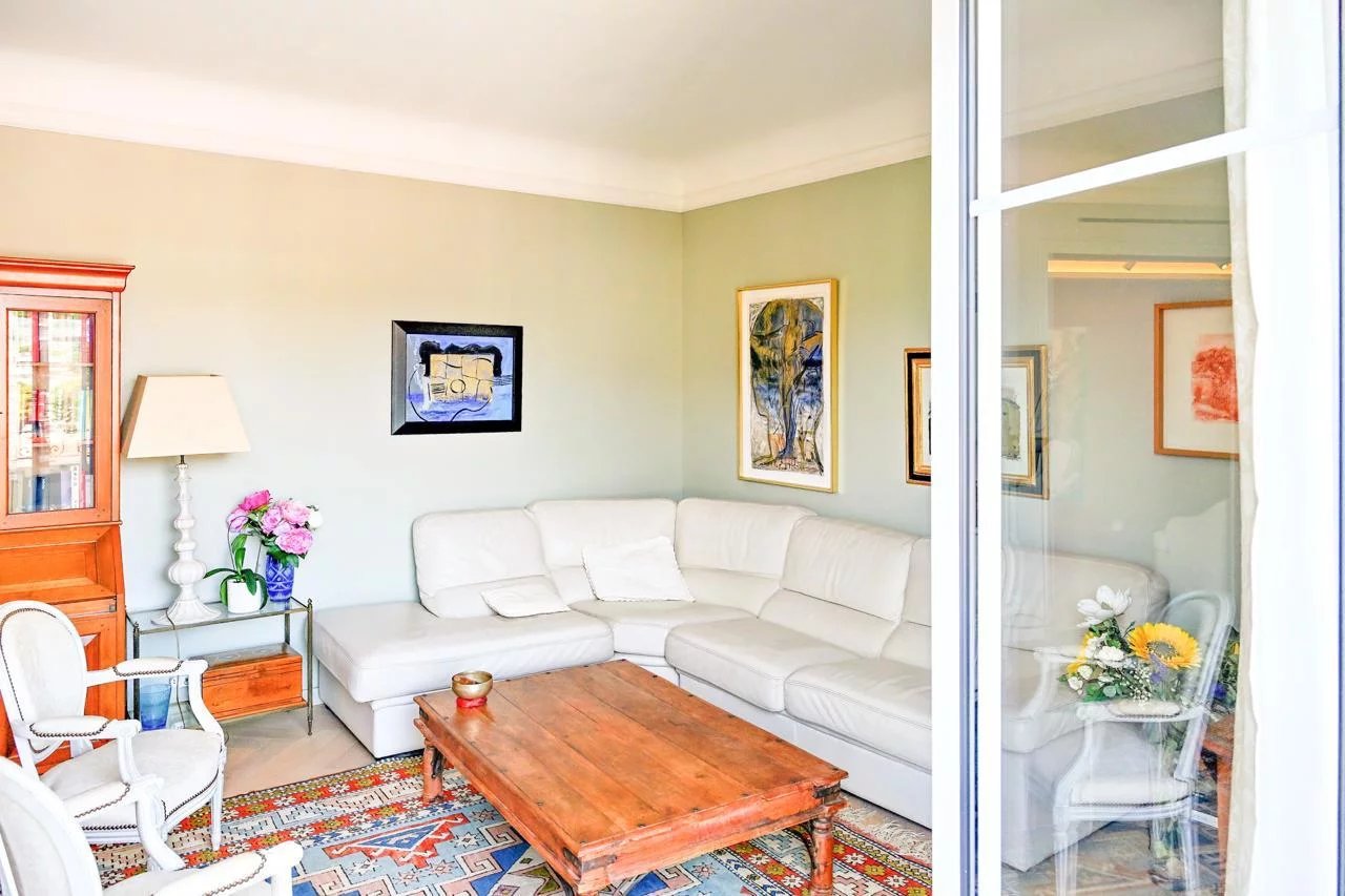 Salon lumineux d'un appartement bourgeois à Cannes, avec canapé blanc et table basse en bois.