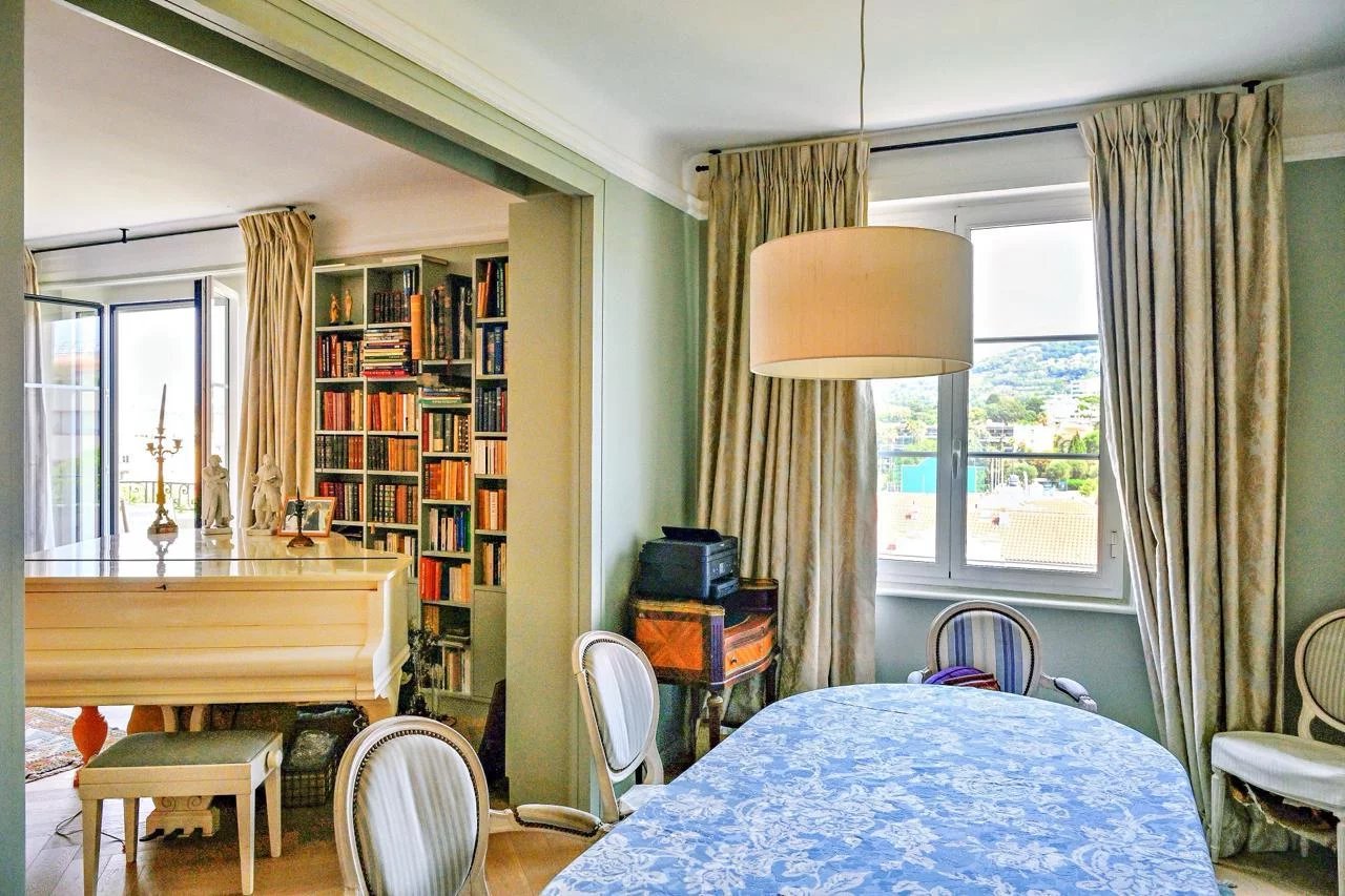 Intérieur d'un appartement bourgeois à Cannes avec salle à manger et bibliothèque.