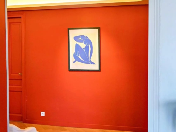 Intérieur d'un appartement bourgeois à Cannes avec un mur rouge et une œuvre d'art moderne.