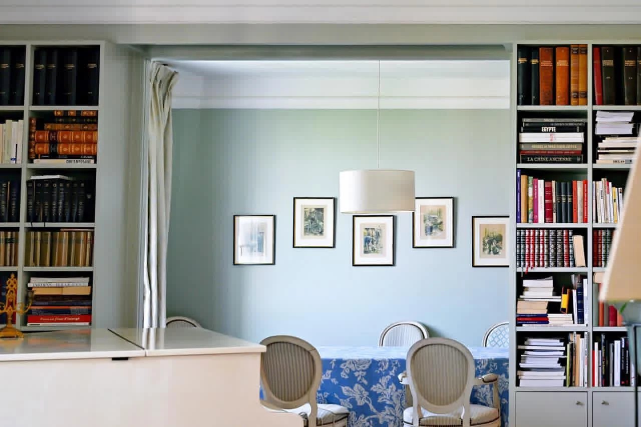 Intérieur d'un appartement bourgeois à Cannes avec bibliothèque et salle à manger lumineuse.