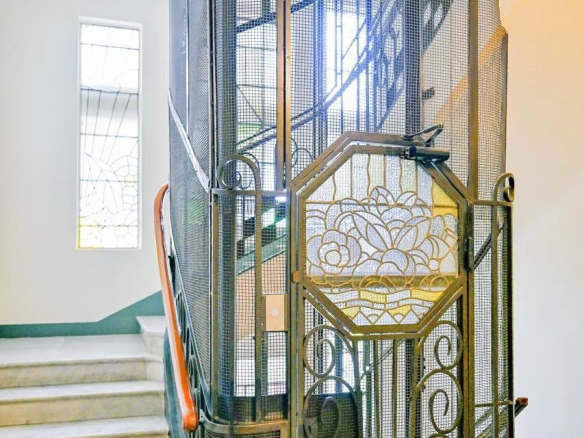Escalier d'une résidence bourgeoise à Cannes avec une porte en fer forgé et des fenêtres en vitraux.