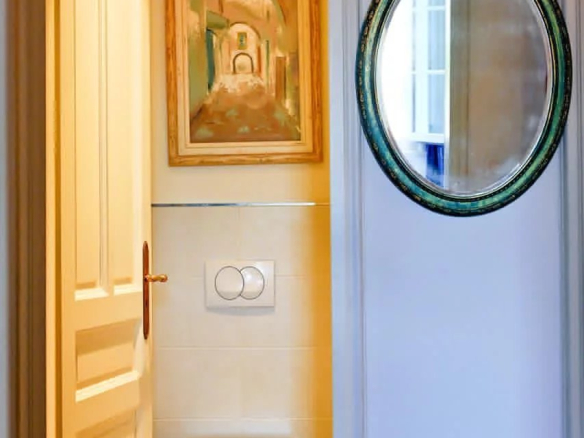 Toilettes dans un appartement bourgeois à Cannes, avec un miroir et une peinture au mur.