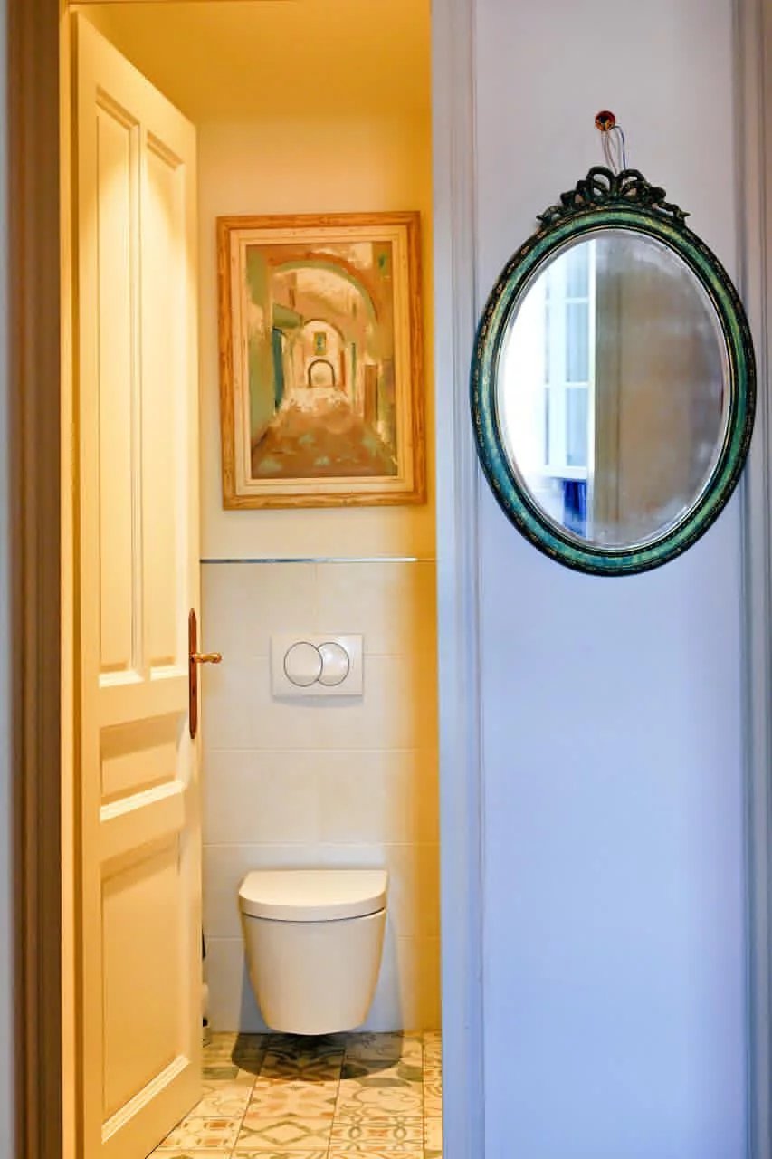 Toilettes dans un appartement bourgeois à Cannes, avec un miroir et une peinture au mur.