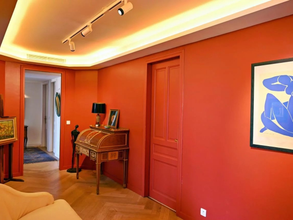 Intérieur d'un appartement bourgeois à Cannes avec murs rouges et éclairage moderne.