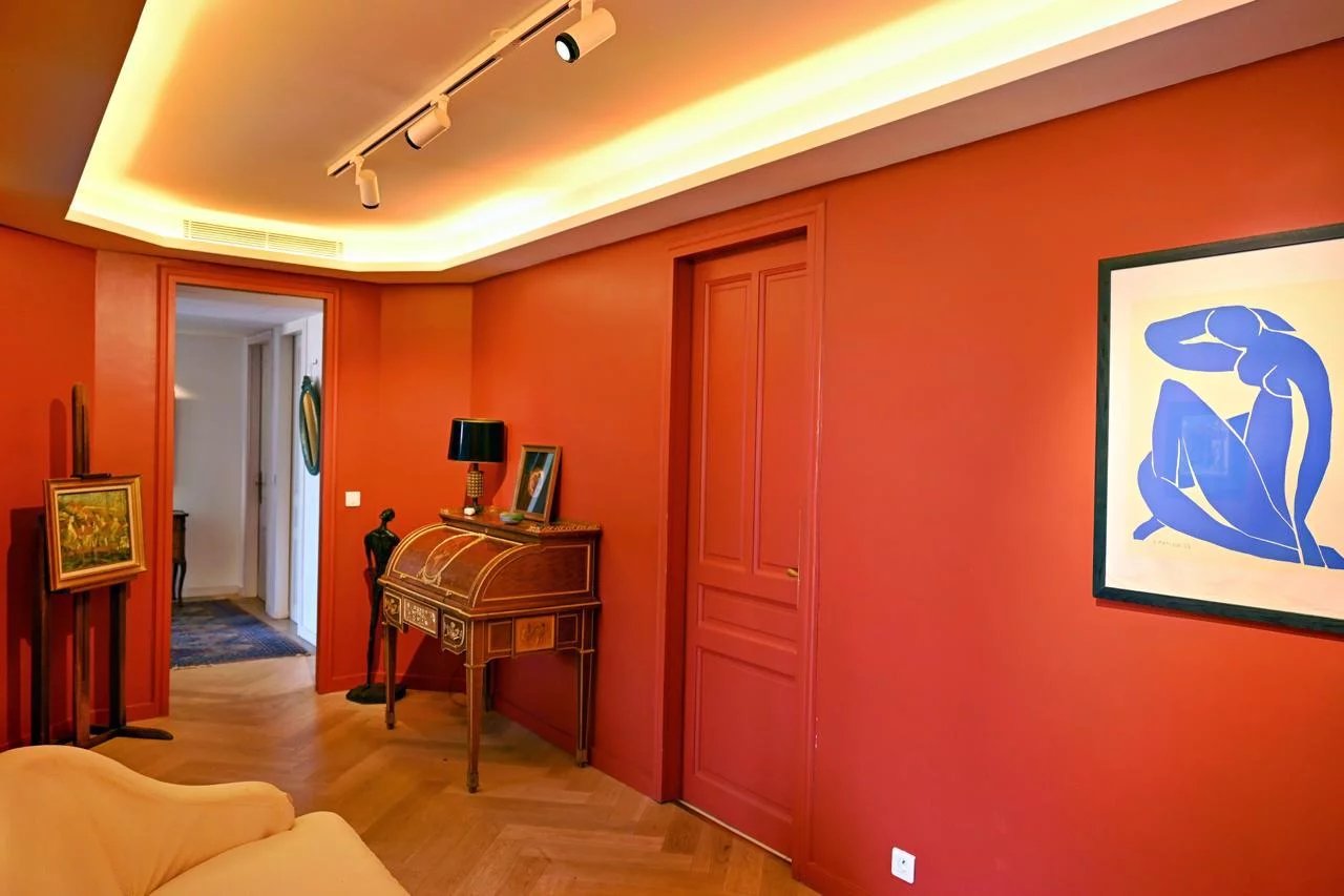 Intérieur d'un appartement bourgeois à Cannes avec murs rouges et éclairage moderne.