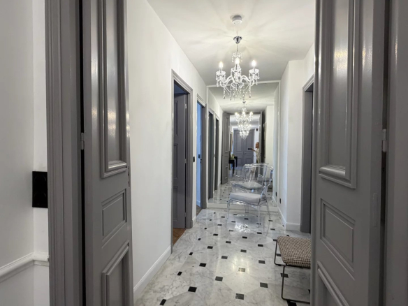 Couloir d'un appartement rénové à Cannes avec carrelage en marbre et lustres élégants.