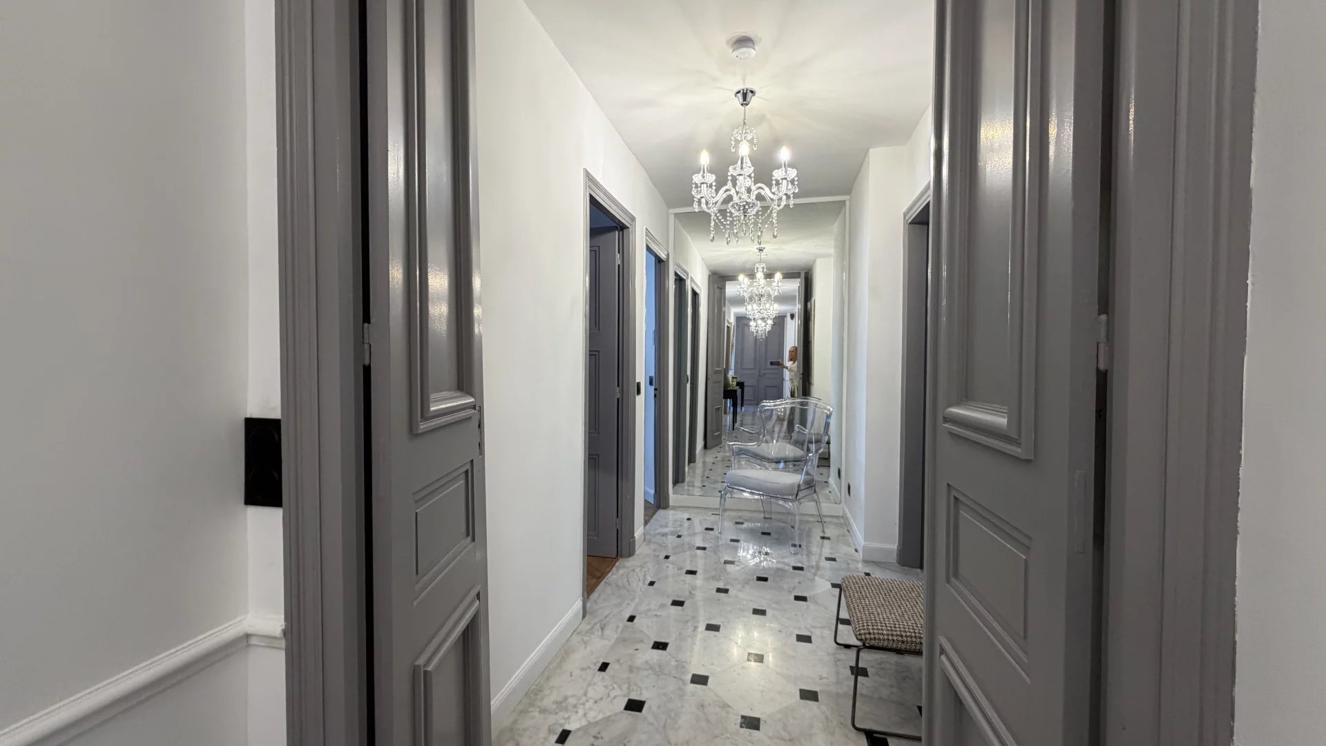 Couloir d’un appartement à Cannes Couloir d'un appartement rénové à Cannes avec carrelage en marbre et lustres élégants.