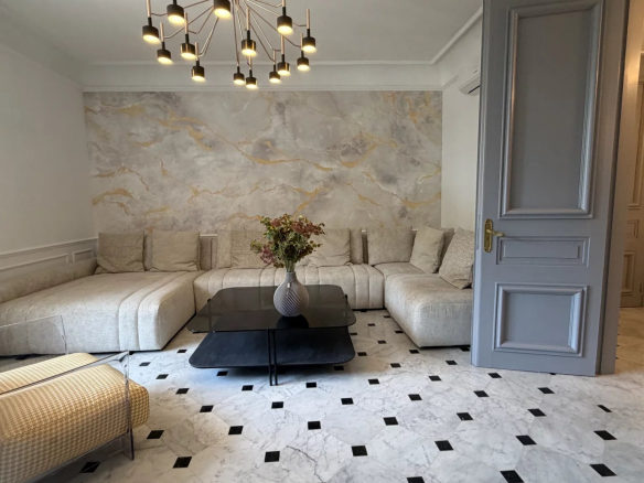 Salon spacieux avec canapé moderne et décoration élégante, murs en marbre et sol en carreaux noirs et blancs.